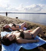 バンクーバーの浜辺には日光浴を楽しむ女性の姿も（共同）